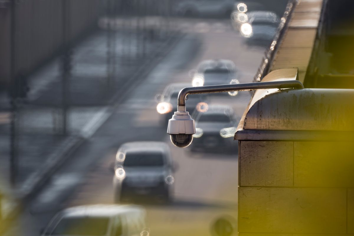 Pan-tilt-zoom security camera overlooking a lane of vehicles at dusk