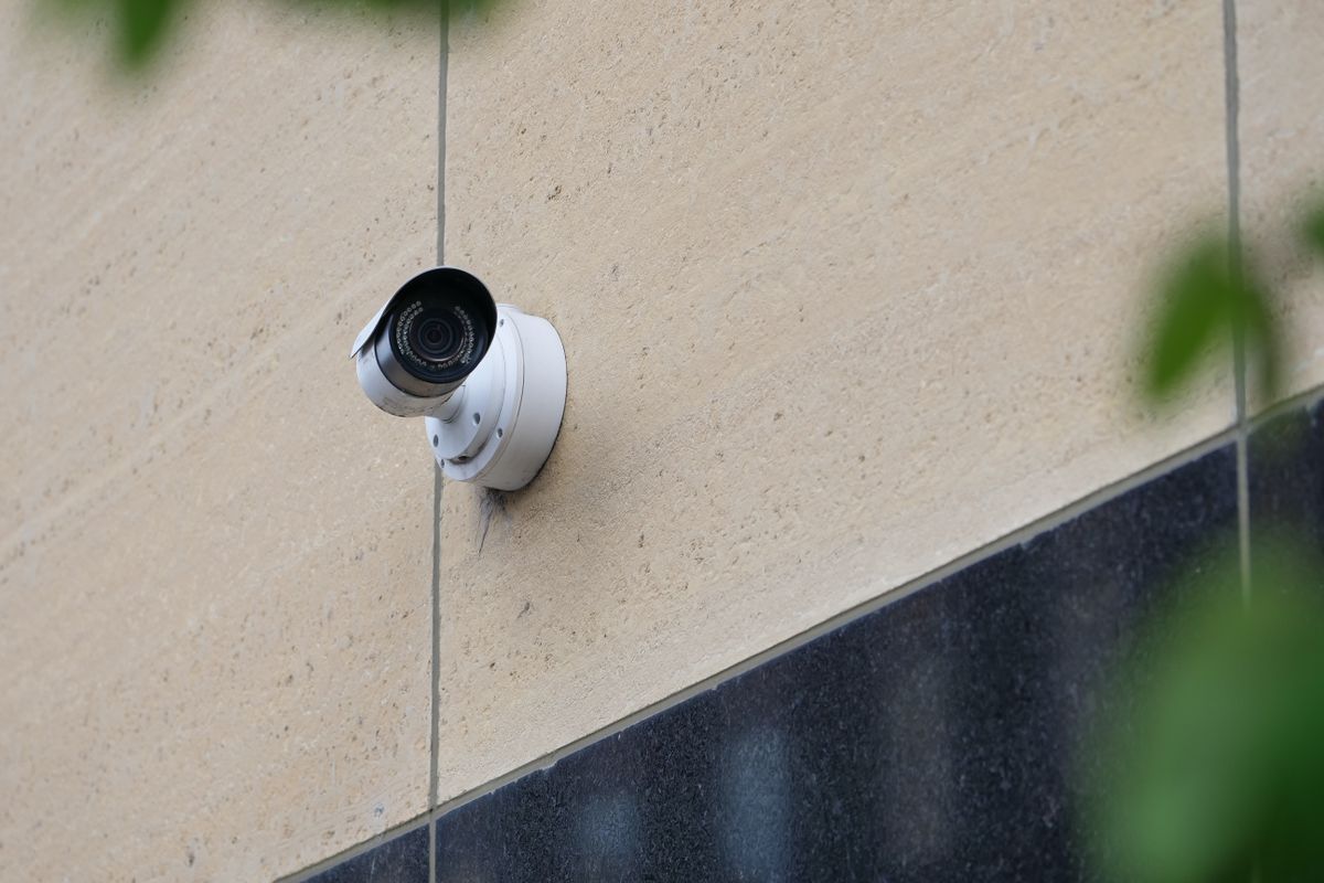 White security camera mounted on the stone wall of a commercial building