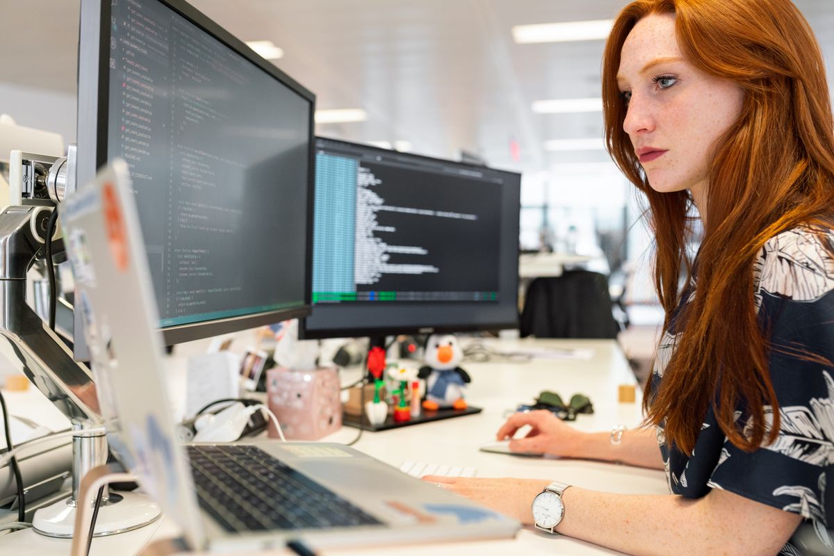 Analyst working at a multi-monitor workstation in a bright modern office