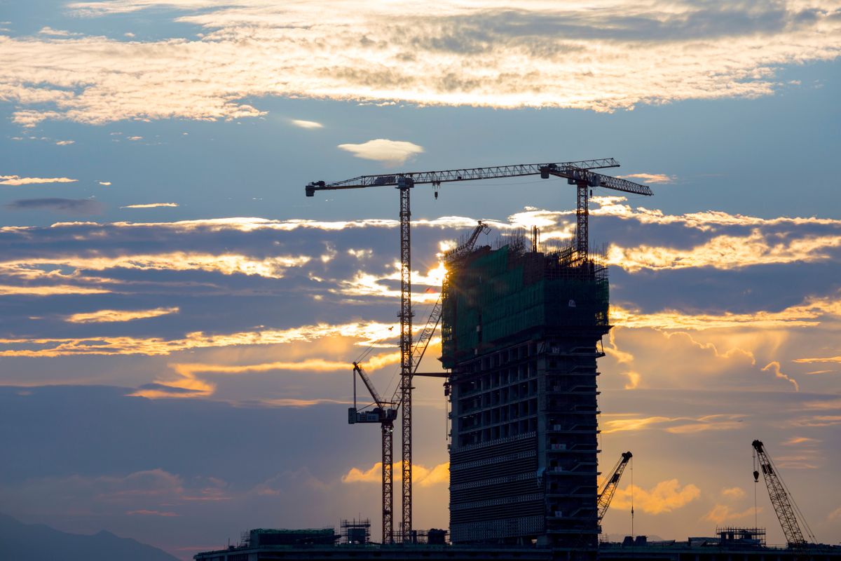 Tower cranes over a building under construction at sunset